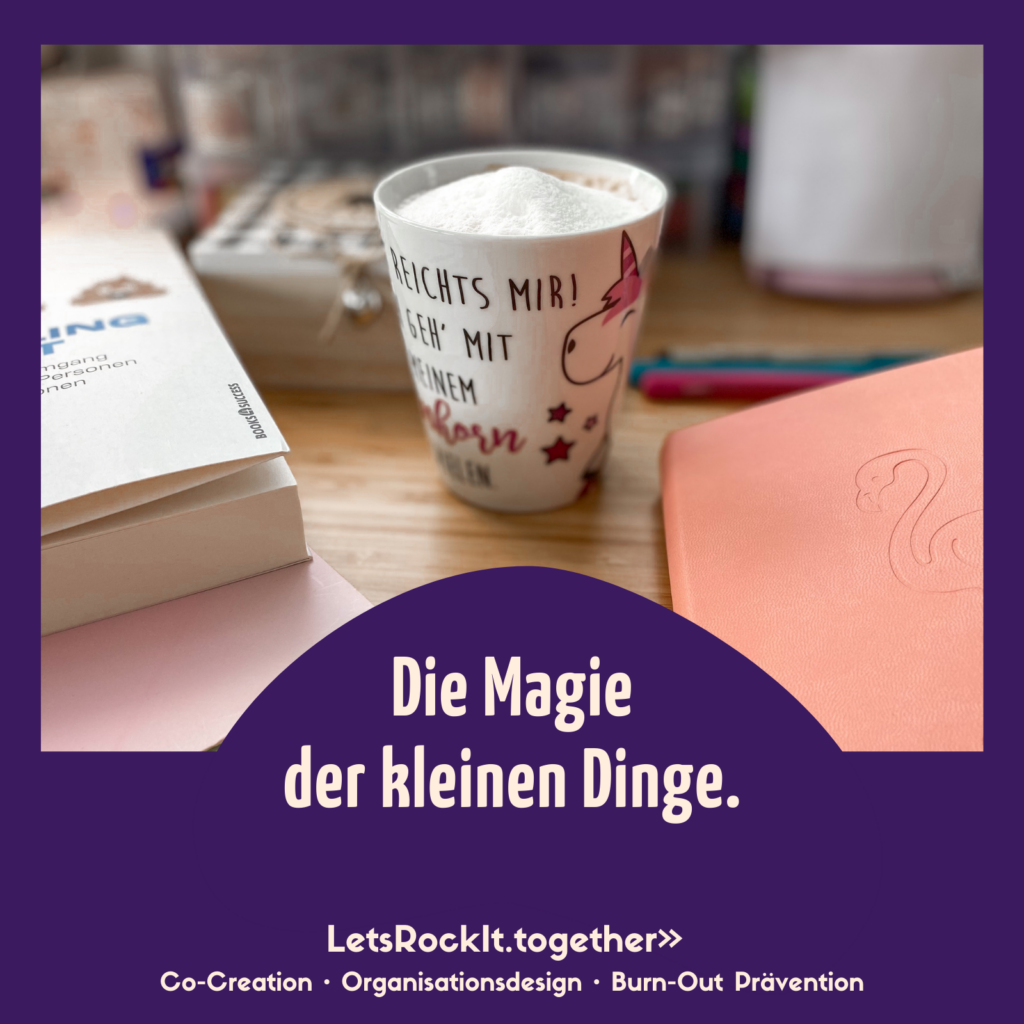 Ein aufgeschäumter Cappuccino in einer Einhorntasse steht auf einem Schreibitsch